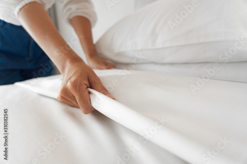Female Hand set up white bed sheet in bedroom photo