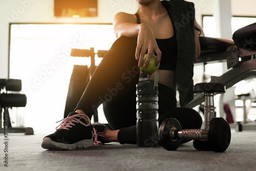 Fototapeta Naklejka Na Ścianę i Meble -  Woman holding apple after fitness exercise at gym. Healthy and lifestyle concept.