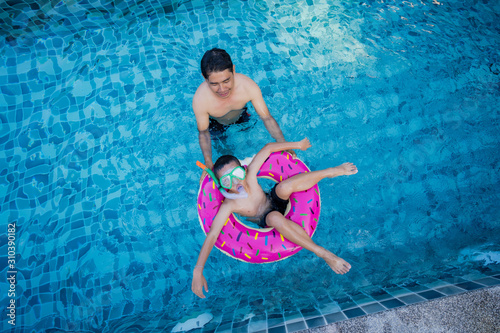 View of man and boy with swim ring floating in the swimming pool