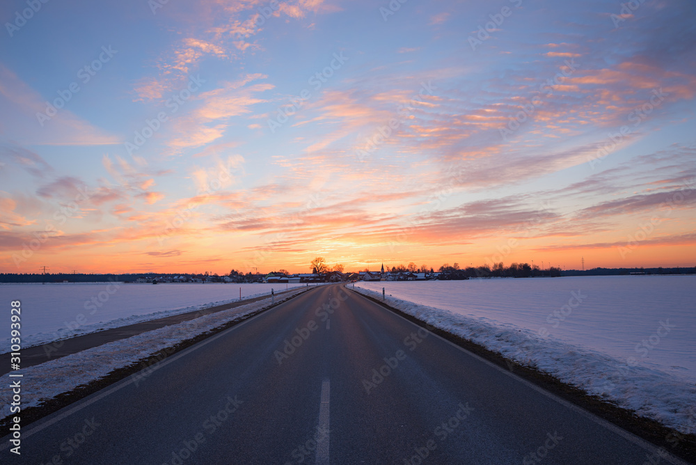 straight country road in winter landscape at sunset, Brunnthal village, upper bavaria straight country road in winter landscape at sunset, Brunnthal village, upper bavaria
