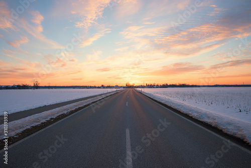 straight country road in winter landscape at sunset, Brunnthal village, upper bavaria
