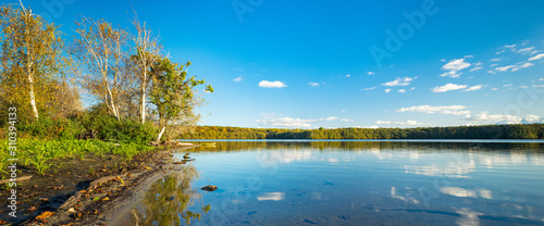 See im Müritz Nationalpark umgeben von Wald im Herbst unter blauem Himmel © AVTG