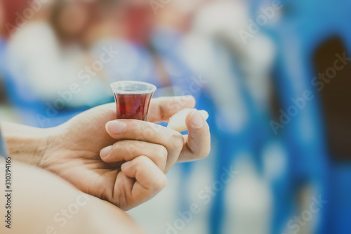 Billede på lærred Hands hold a red wine cup in Holy communion