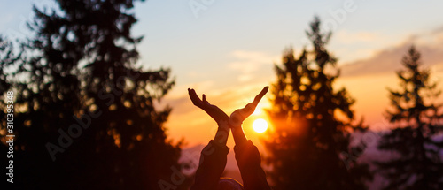 sun in hands. Sunset on the background of raised hands. © jozefklopacka