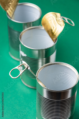 Valokuva Top view of three empty tin cans with rings, diagonally, on green background, pr