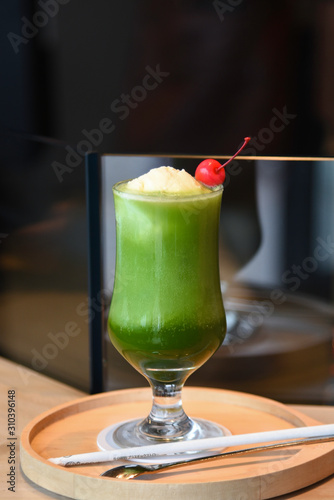 Glass of fresh and healthy green smoothie on wooden teble.