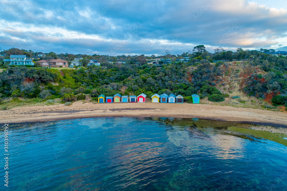 Colorful beach boxes reflecting in the ocean at Ranelagh beach. Mornington Peninsula, Victoria, Australia