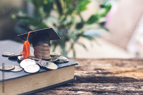 Tableau sur toile Saving money financial concept, congratulations graduates cap on top of the money with book