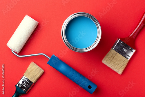 Fototapeta Naklejka Na Ścianę i Meble -  Can of blue paint with brushes and paint roller on red background. Top view. Repair concept.