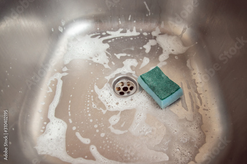 Kitchen cleaning and cleaning. Blue kitchen sponge with metal kitchen sink