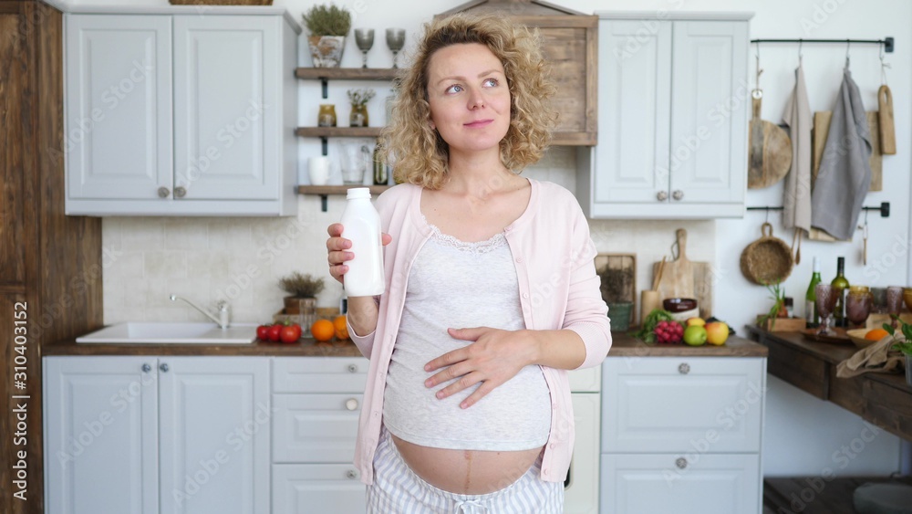 Young Pregnant Woman Taking Medicine Against Heartburn On Her Kitchen. Symptomatic Relief. Young Pregnant Woman Taking Medicine Against Heartburn On Her Kitchen. Symptomatic Relief.