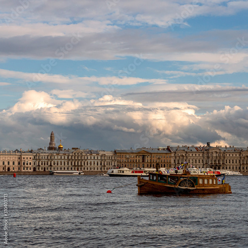 vintage motor boat on the Neva River in St. Petersburg against the backdrop of modern pleasure boats and a beautiful promenade