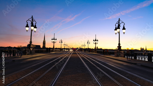 Fototapeta Naklejka Na Ścianę i Meble -   Selective focus of Tramway rails tracks in sunset light at Pont de pierre crossing Garonne river, Bordeaux,France
