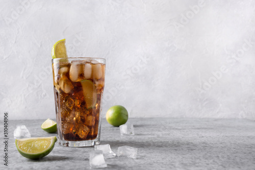 Cocktail Cuba Libre or long island iced tea with rom, cola, lime and ice in glass on grey stone table. Horizontal orientation. photo