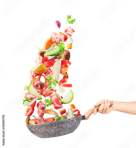 Cooking concept. Vegetables and meat are flying out of the pan isolated on white background. Healthy food. photo