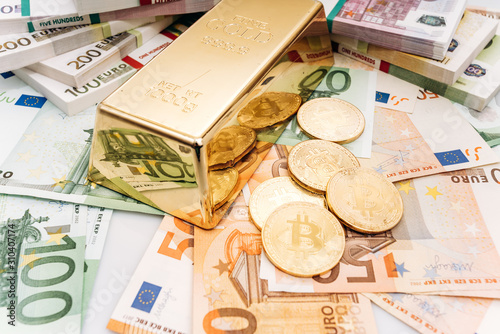 Bitcoin BTC Gold coins with bills of euro banknotes and gold bullion. Bitcoin and gold lie on Euro banknotes