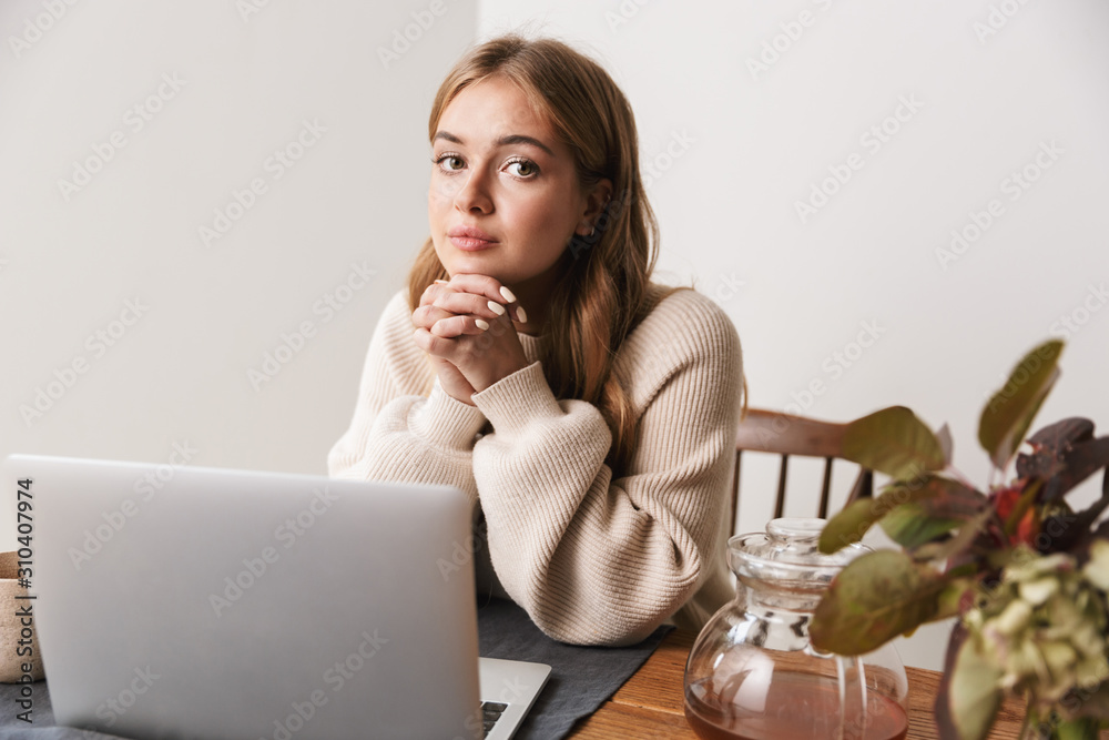 Image of young caucasian woman using laptop and drinking tea