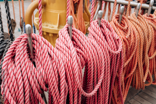 Old sailboat, closeup of wooden cleats with nautical moored ropes.