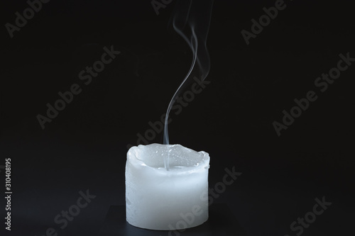 Smoke rising from a dipped candle. Blue smoke of a candle in dark background, concept of air pollution from oil products burning photo