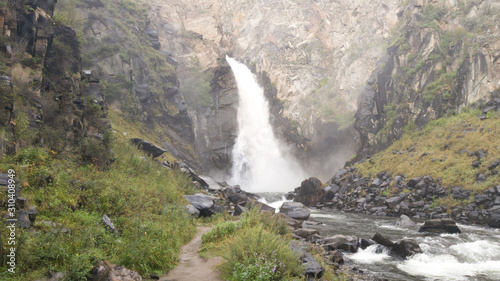 Big beautiful waterfall Kurkure in the Altai Republic in Russia. Summer trip to the Altai. Selective focus