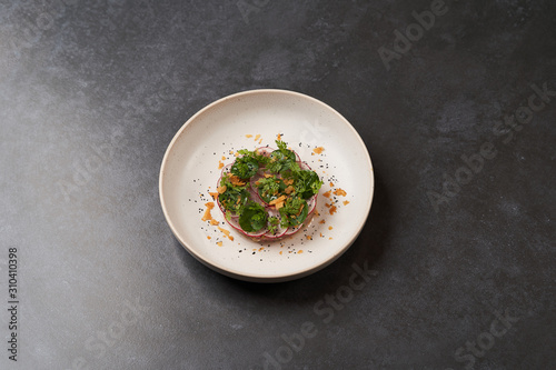 Fresh beef tartare dish with fresh vegetables in white plate