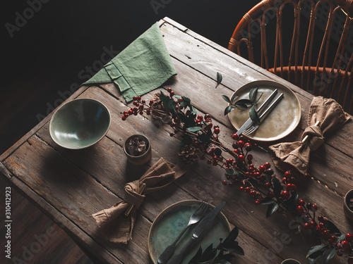 Holiday table setting with Linen napkins and the red berry branch decor. Scandinavian style. Wooden table. The concept of the holiday. Close up