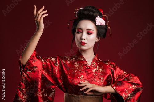 Quadro su tela Image of young geisha woman in traditional japanese kimono dancing