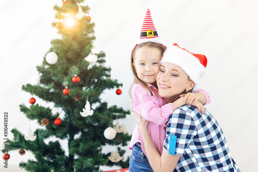Christmas, family and holidays concept - Festive mother and daughter on the couch at home in the living room Christmas, family and holidays concept - Festive mother and daughter on the couch at home in the living room