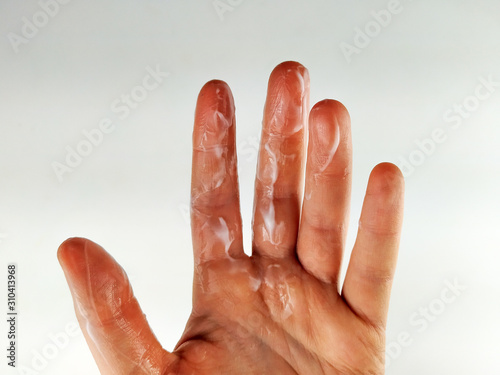 Hand covered in hand cream or body lotion on white background while moisturizing the body and doing the body care routine