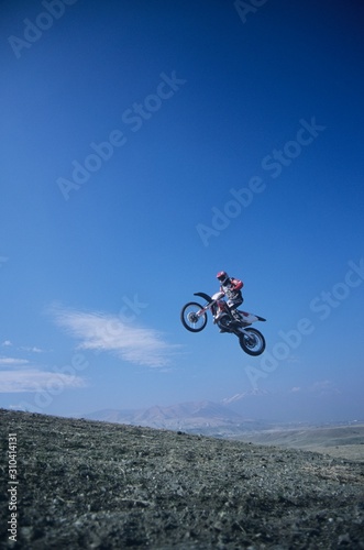 Mountain Biker Jumping Against Blue Sky