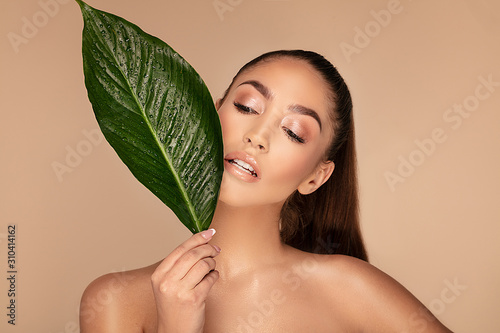 Beautiful brunette woman with green leaf. photo