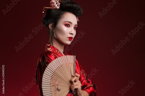 Fotomurale Image of young geisha woman in japanese kimono holding wooden hand fan