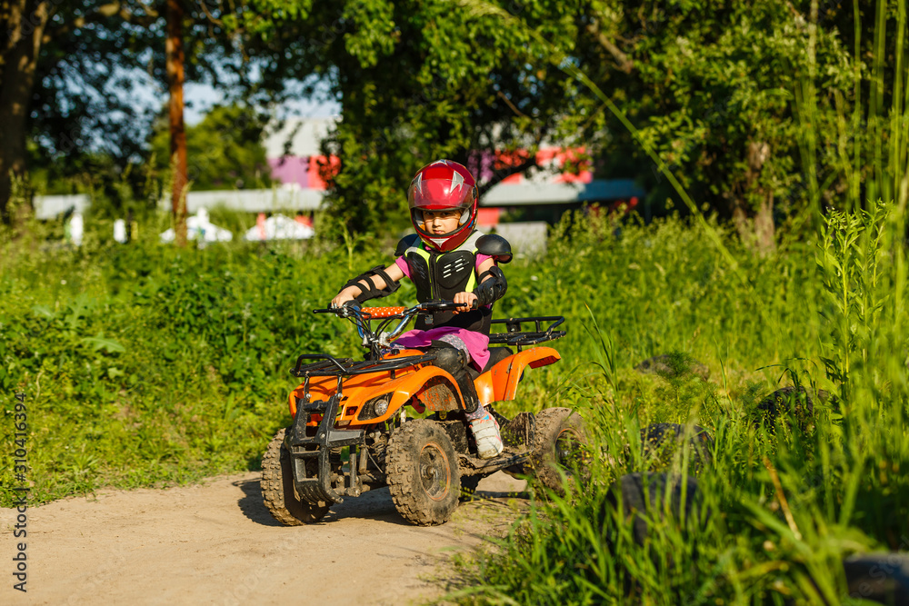 Little girl riding ATV quad bike in race track Little girl riding ATV quad bike in race track