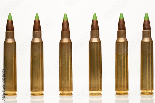 A group of 5.56 calibar, green tip bullets ordered into the line on white background photo