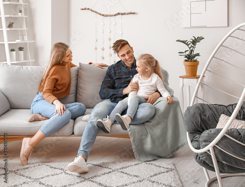 Happy young family sitting on sofa at home