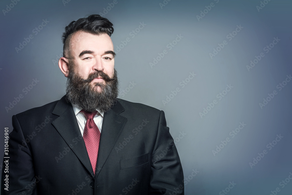 Adult bearded man in a suit with mohawk hairstyle on a blue background Adult bearded man in a suit with mohawk hairstyle on a blue background
