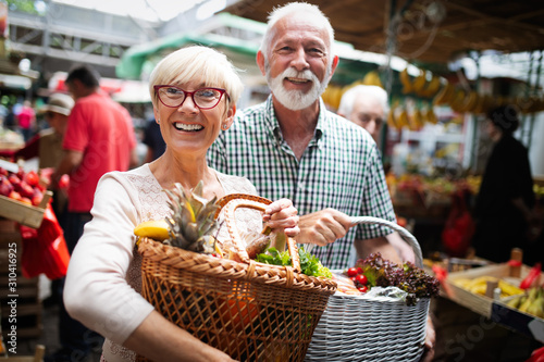 Mature couple shopping vegetables and fruits on the market. Healthy diet.