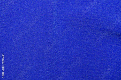 The texture of a knitted woolen fabric textile in classic blue trendy color. Abstract background for design with soft waves