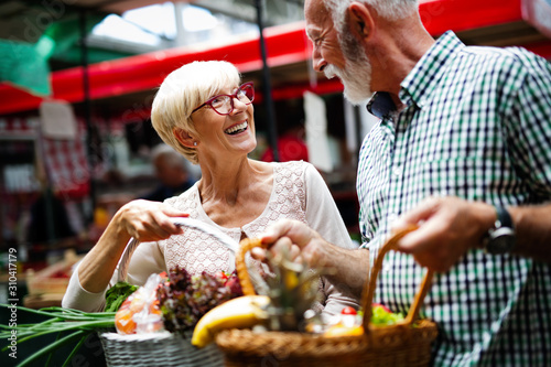 Portrait of beautiful elderly couple in market buing food photo