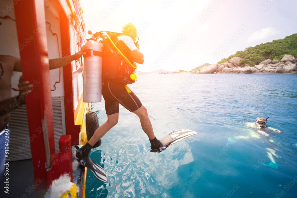 Male diver jumps into the sea from a yacht.