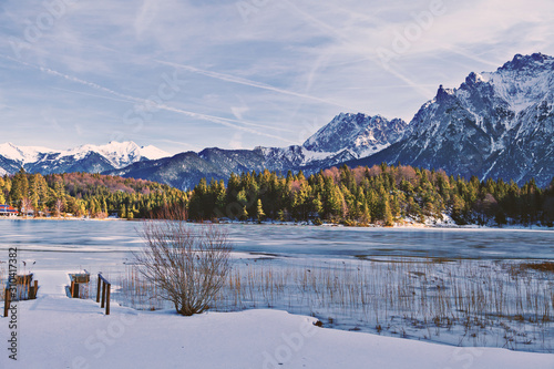 Zugefrorener Bergsee mit steilen Felswänden im Hintergrund und verschneiter Landschaft