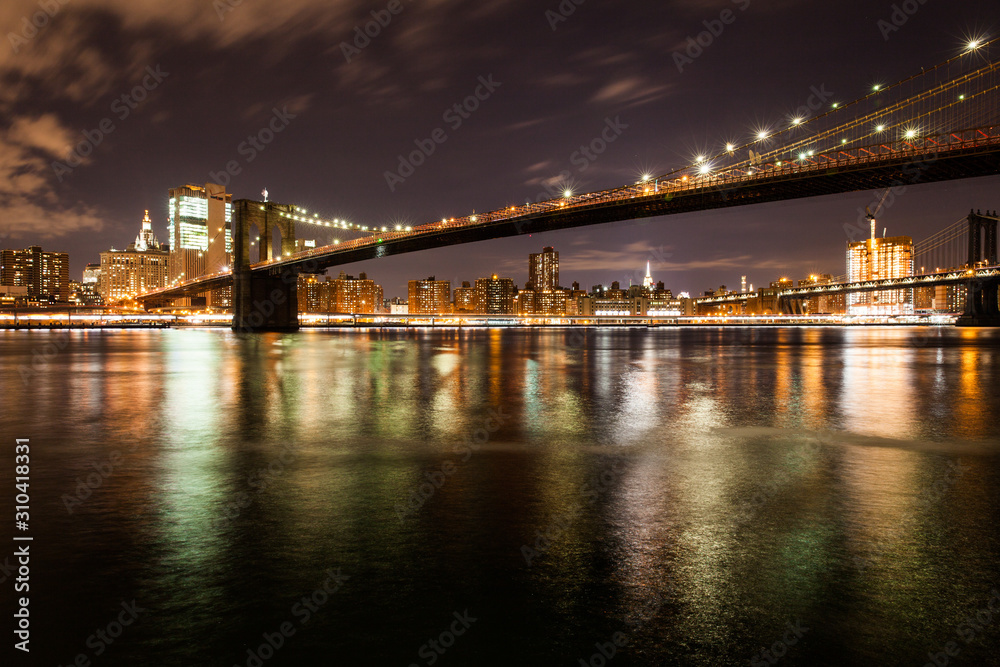 Brooklyn bridge in the night with reflections on the water