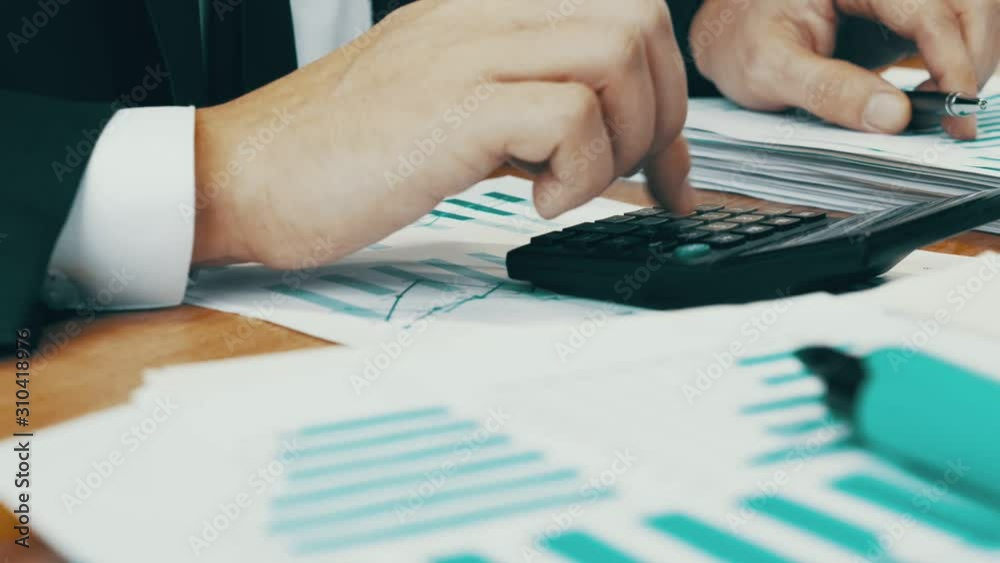 Close up hands are typing on a calculator. The employee performs the calculation of financial results and accounting.