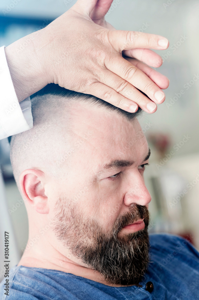 Obraz premium Barber makes styling a mohawk for an adult man.