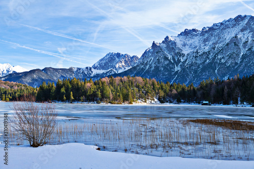 Zugefroener Bergsee mit steilen Felswänden im Hintergrund und verschneiter Landschaft © pengelmann