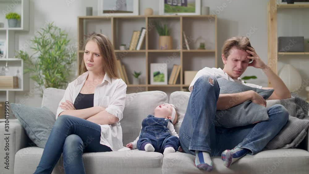 Mom and dad quarrel sitting on a sofa in the presence of a small daughter Mom and dad quarrel sitting on a sofa in the presence of a small daughter