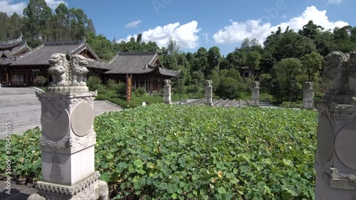 Close by flying next to ancient Chinese buildings and statues in Dazu, Chongqing, China with blue sky and a few clouds in the background.