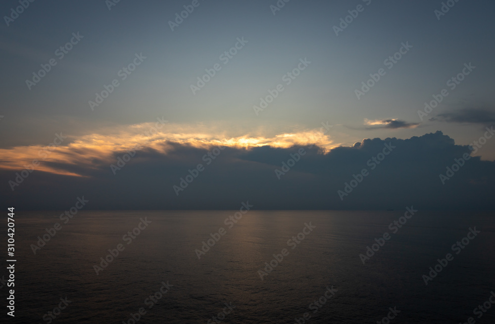 Sunset and dramatic set of clouds drifting over the tropical waters of the Caribbean Sea are lit by the last moments of daylight