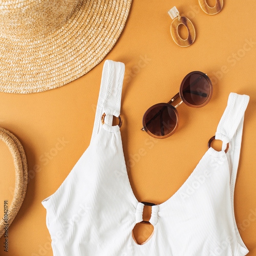 Summer fashion concept with women's swimsuit and accessories on ginger background. Flat lay, top view fashion, beauty, travel blog.