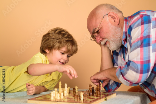 Cute boy developing chess strategy. Chess competition. Childhood and board games. Grandfather and grandson playing chess. Little boy playing chess with grandpa. Brain development and logic concept.